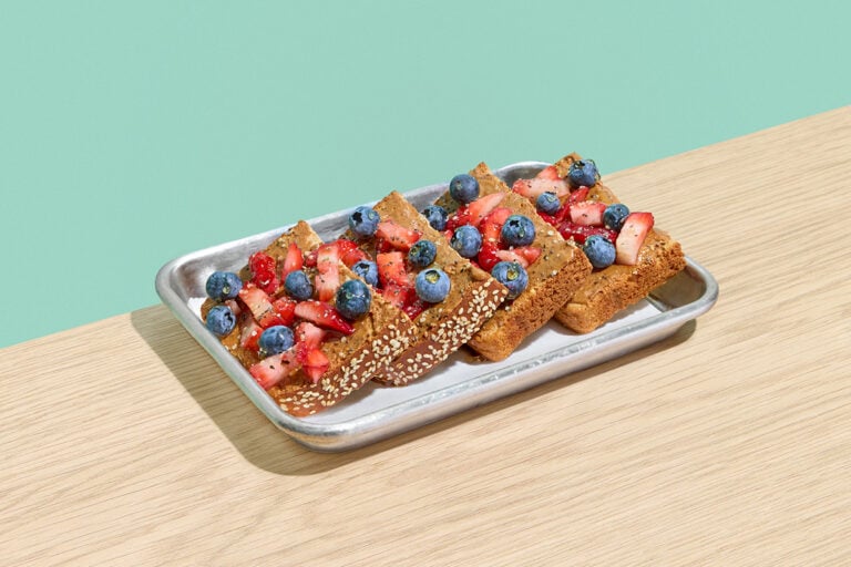 Almond Berry toast on multigrain bread with almond butter, blueberries, strawberries, honey, and a blend of chia and hemp seeds.
