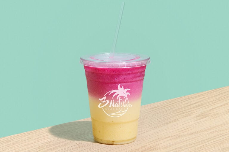 Pink and yellow tropical fruit smoothie in a takeaway cup at 3 Natives Acai Cafe