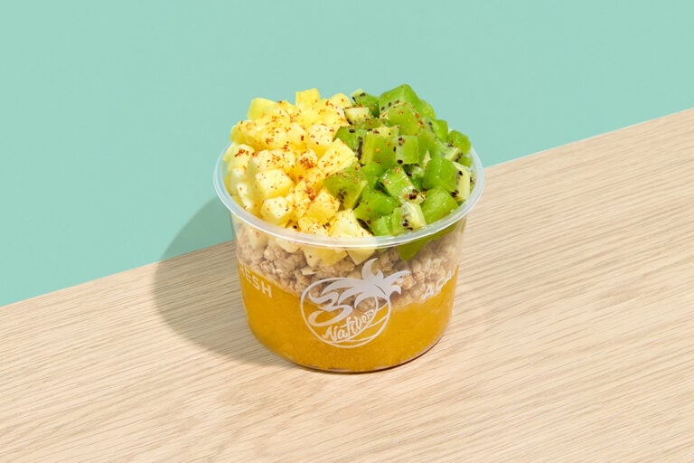 A Mango Tango bowl layered with mango sorbet and granola, topped with diced pineapple and kiwi sprinkled with Tajín seasoning.