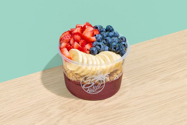 Acai bowl with granola, strawberries, banana slices, blueberries, and honey topping
