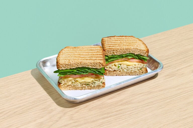 Tuna Melt sandwich on toasted multigrain bread with albacore tuna salad, spinach, tomato, and melted aged cheddar cheese.